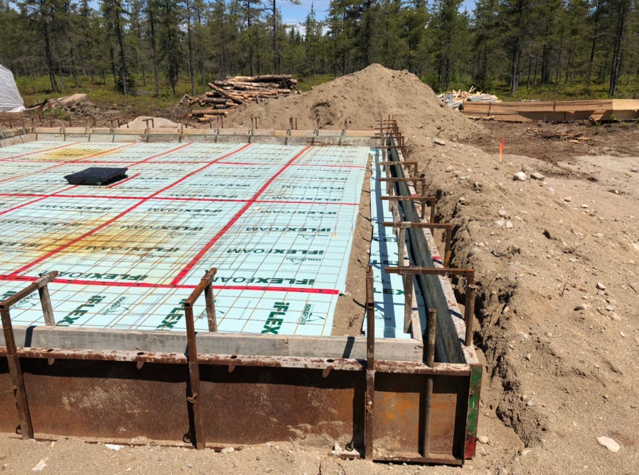 Une fondation en béton est en cours de construction dans un champ de terre.