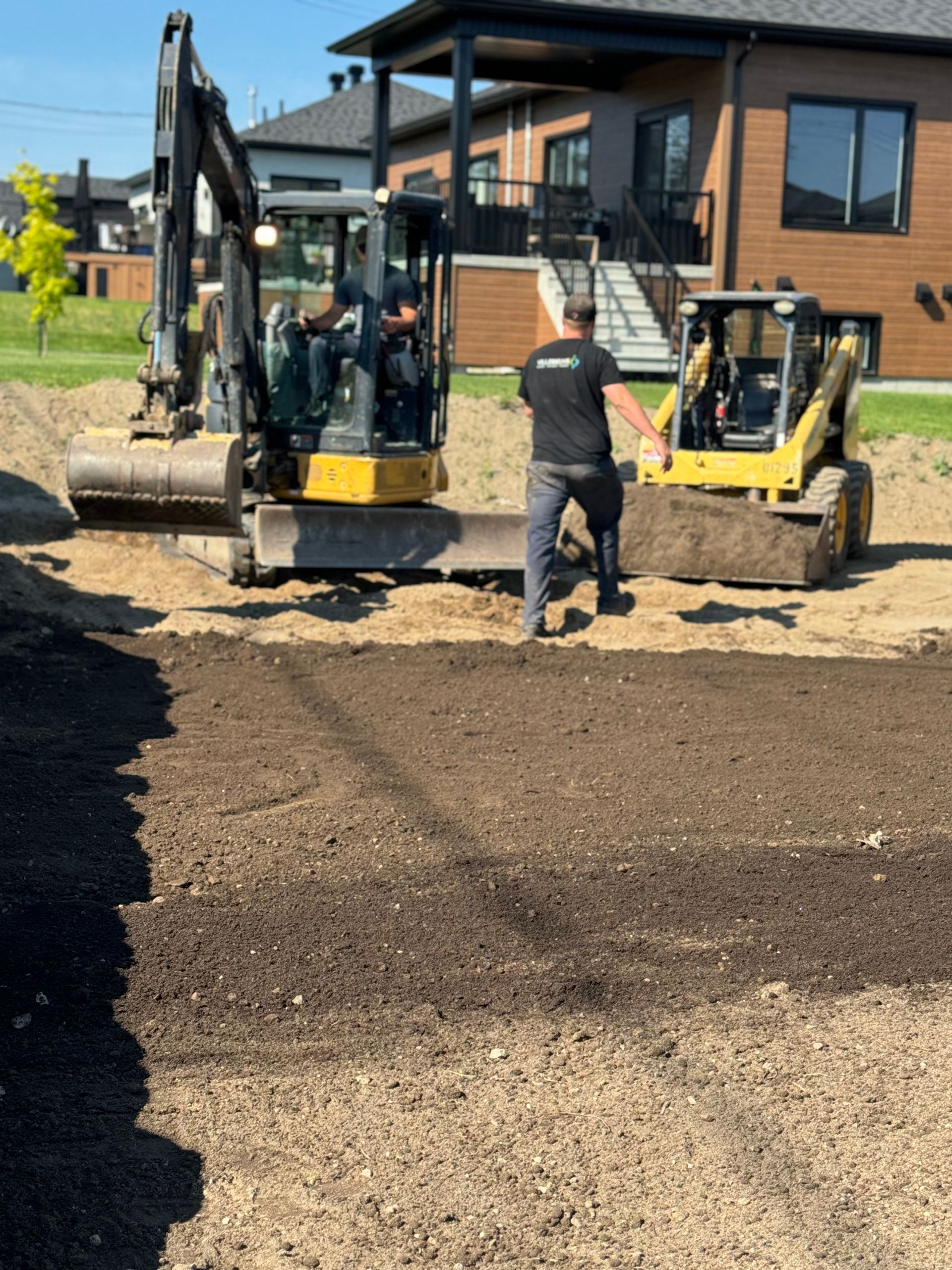 Un homme se tient à côté d'un bulldozer devant une maison