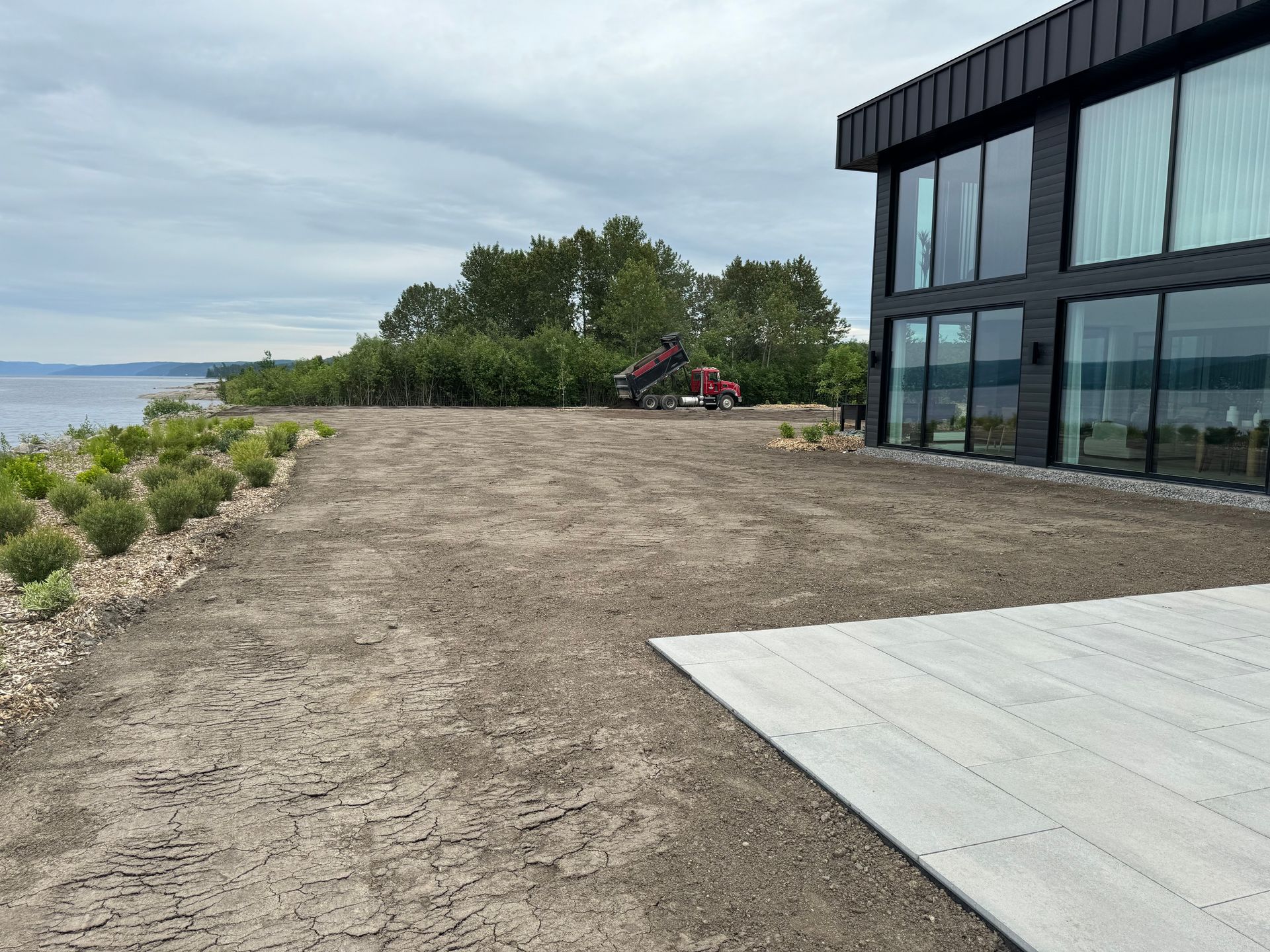 Une grande maison avec beaucoup de fenêtres est située à côté d'un grand plan d'eau.