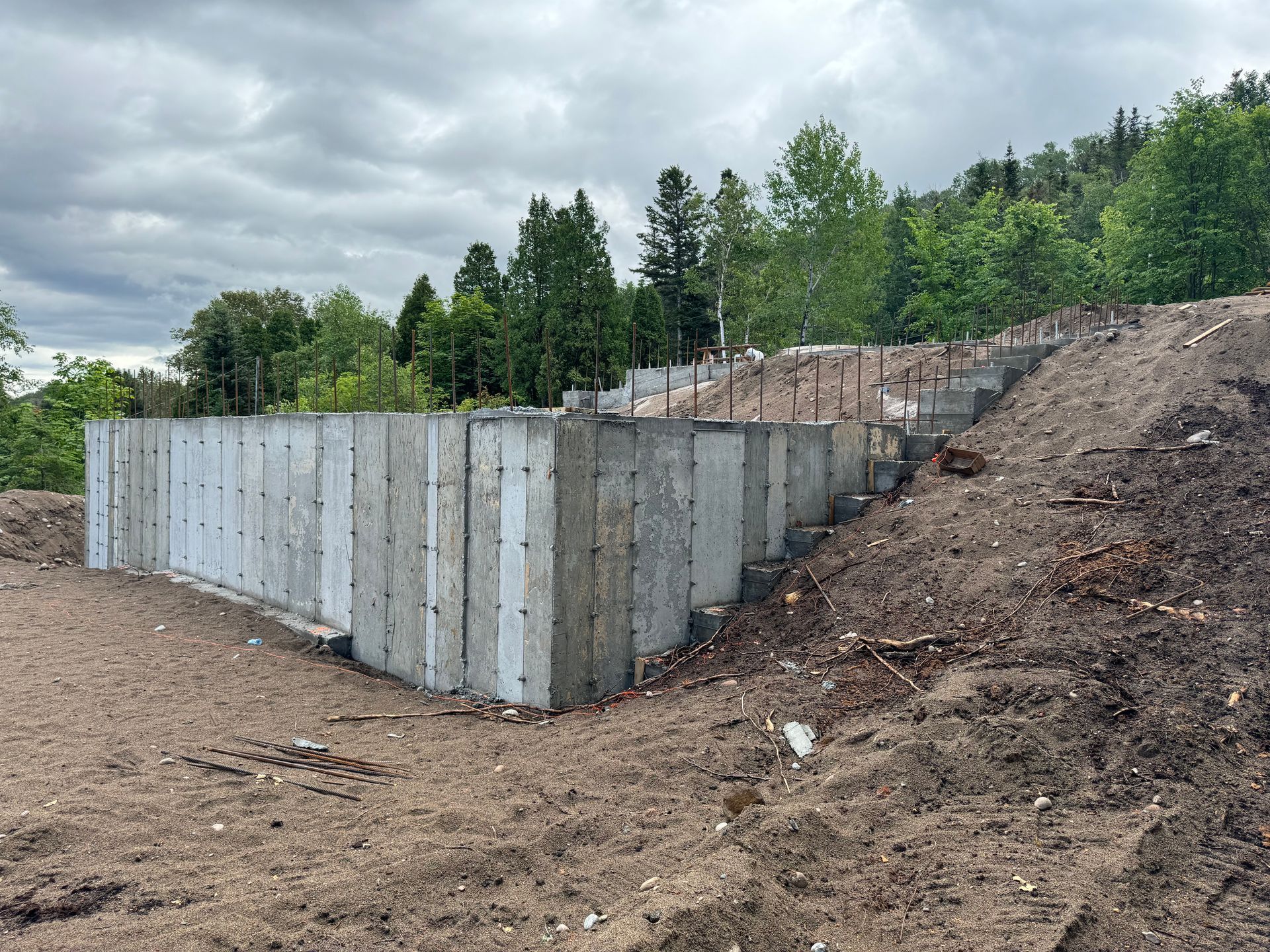 Un grand mur de béton est posé au sommet d'une colline de terre.