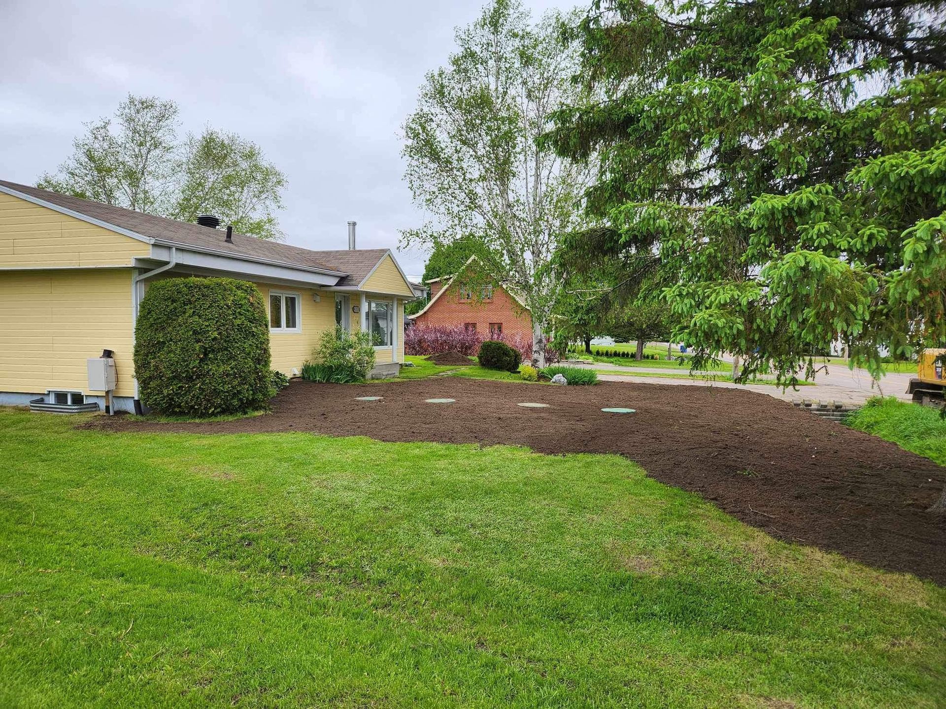 Une maison avec beaucoup d'herbe et d'arbres devant.