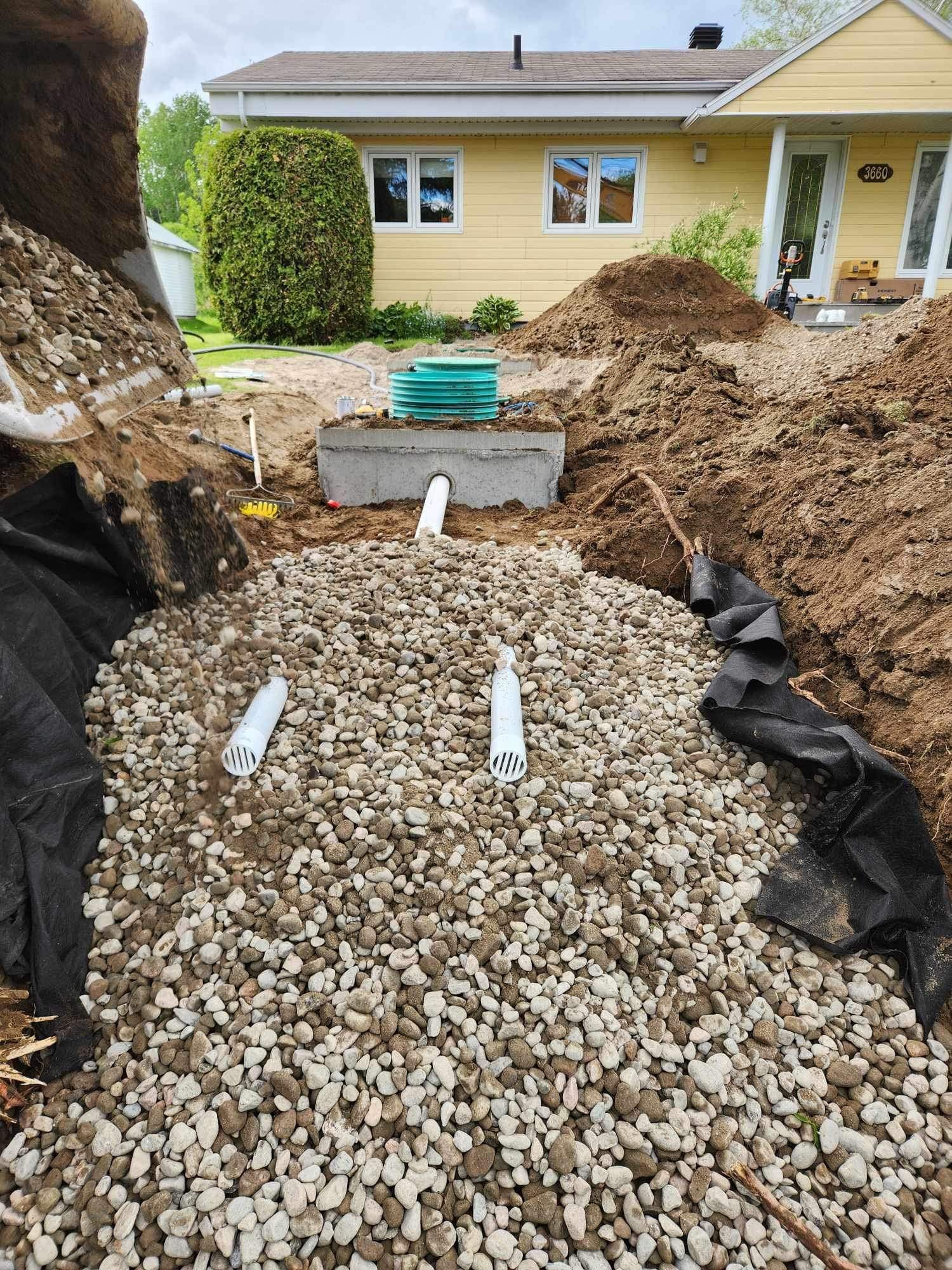 Une fosse septique est en cours d'installation devant une maison.
