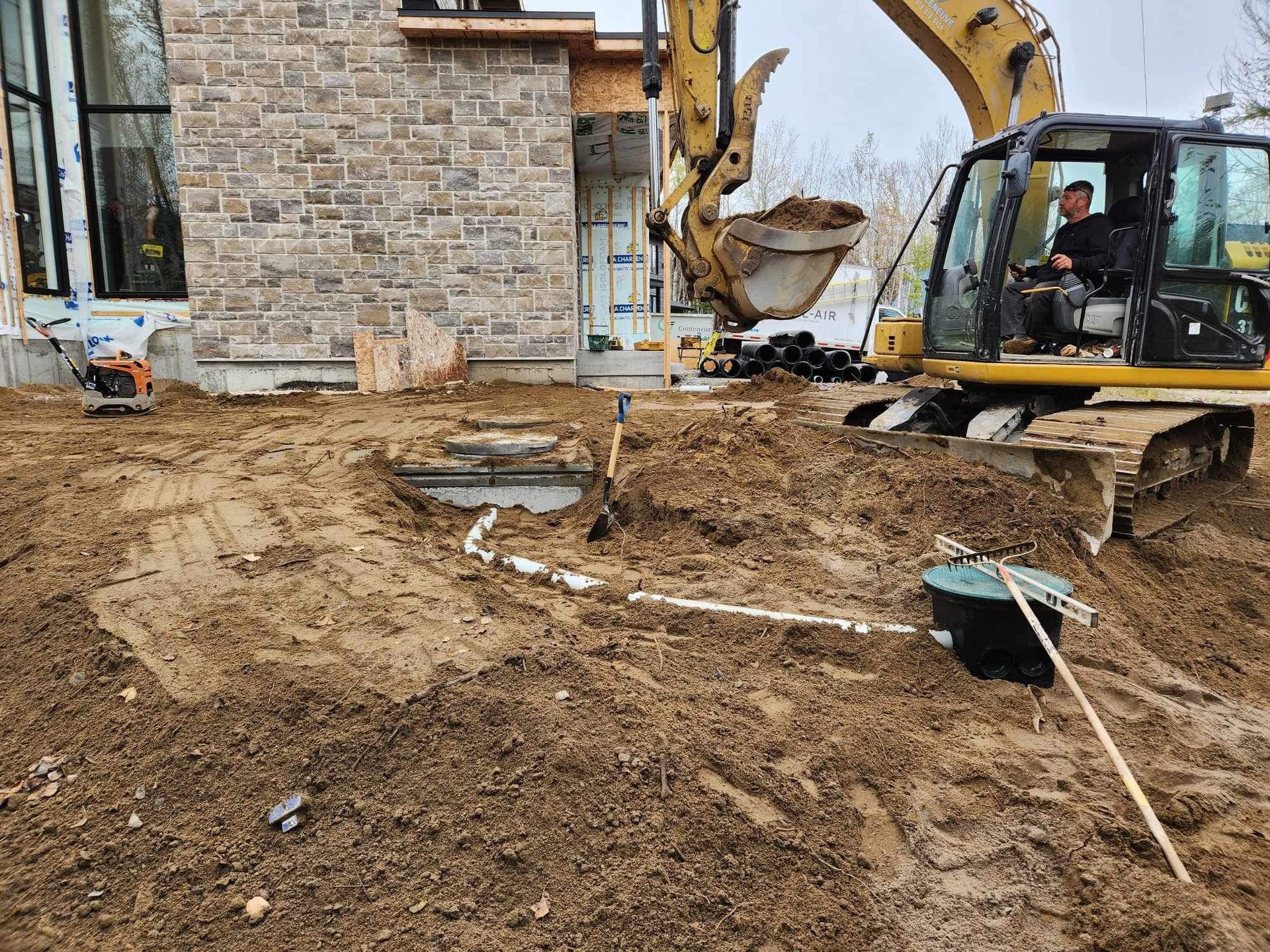 Un bulldozer creuse un trou dans la terre devant un bâtiment en briques.