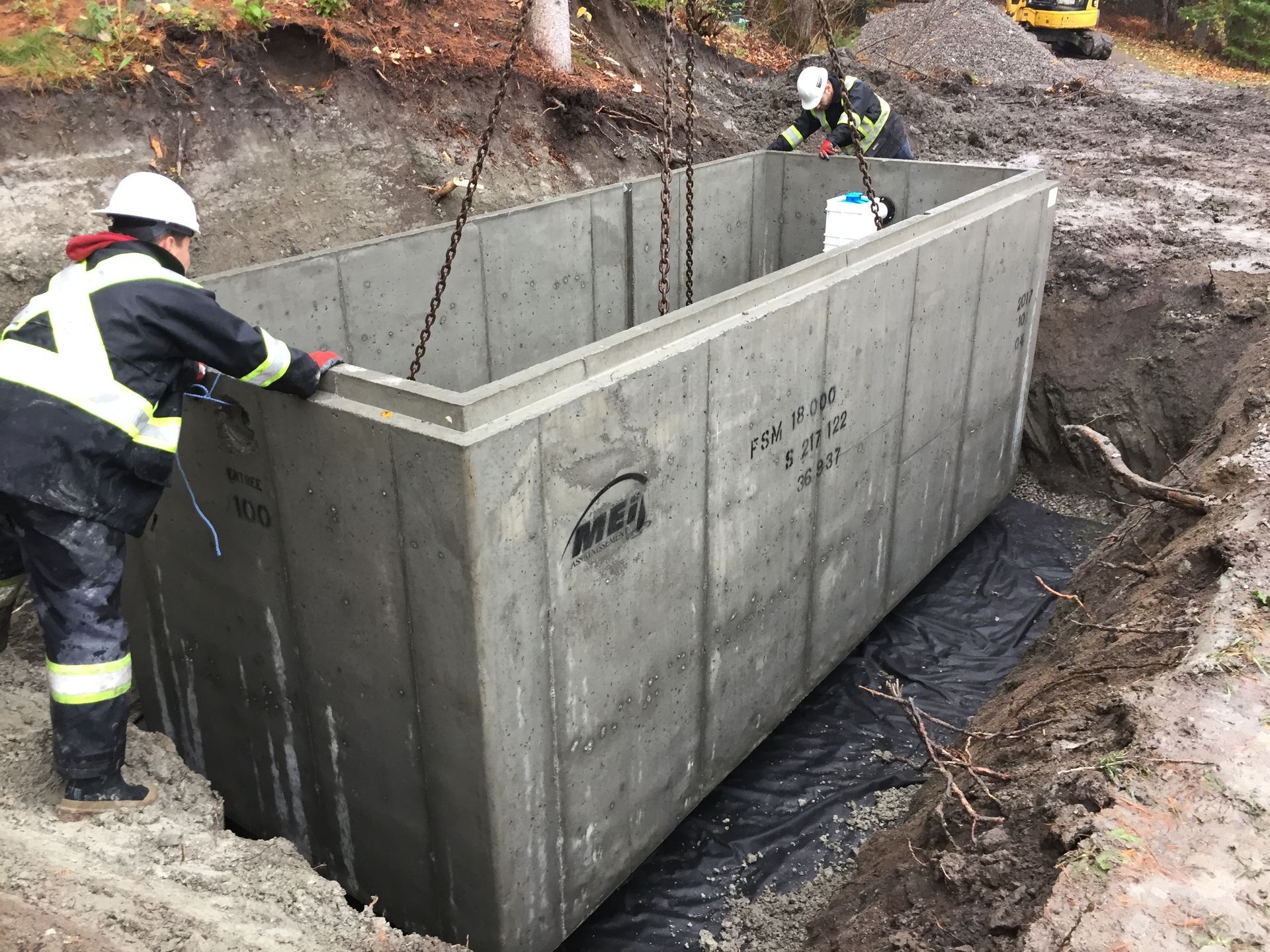 Un groupe d'ouvriers du bâtiment travaille sur un grand réservoir en béton.