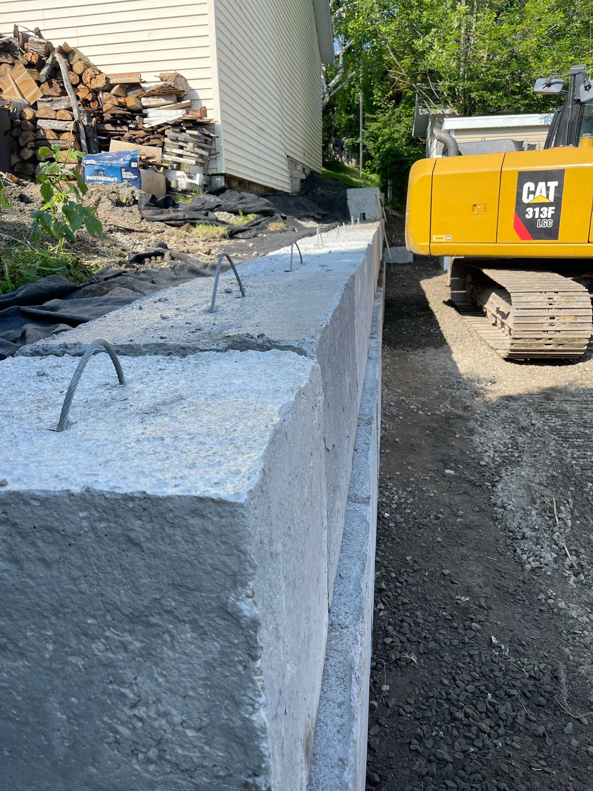 Une excavatrice à chat est assise à côté d'un mur en béton.