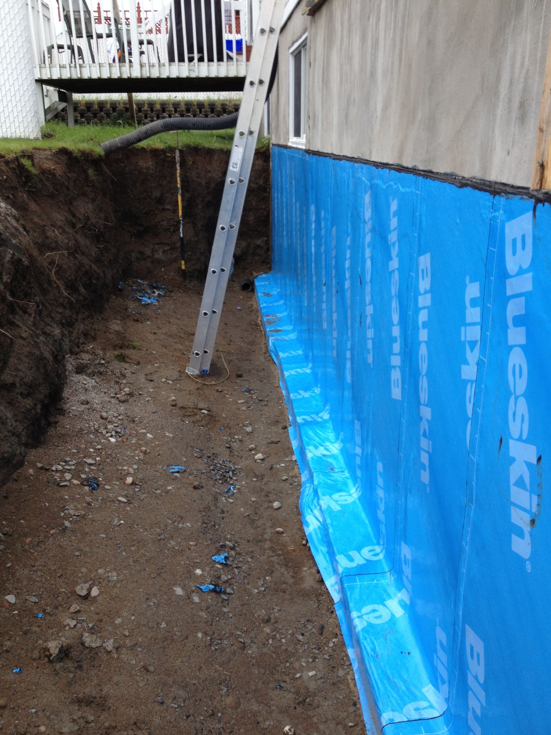Une échelle est posée à côté d'un mur bleu sur lequel est écrit blueskin