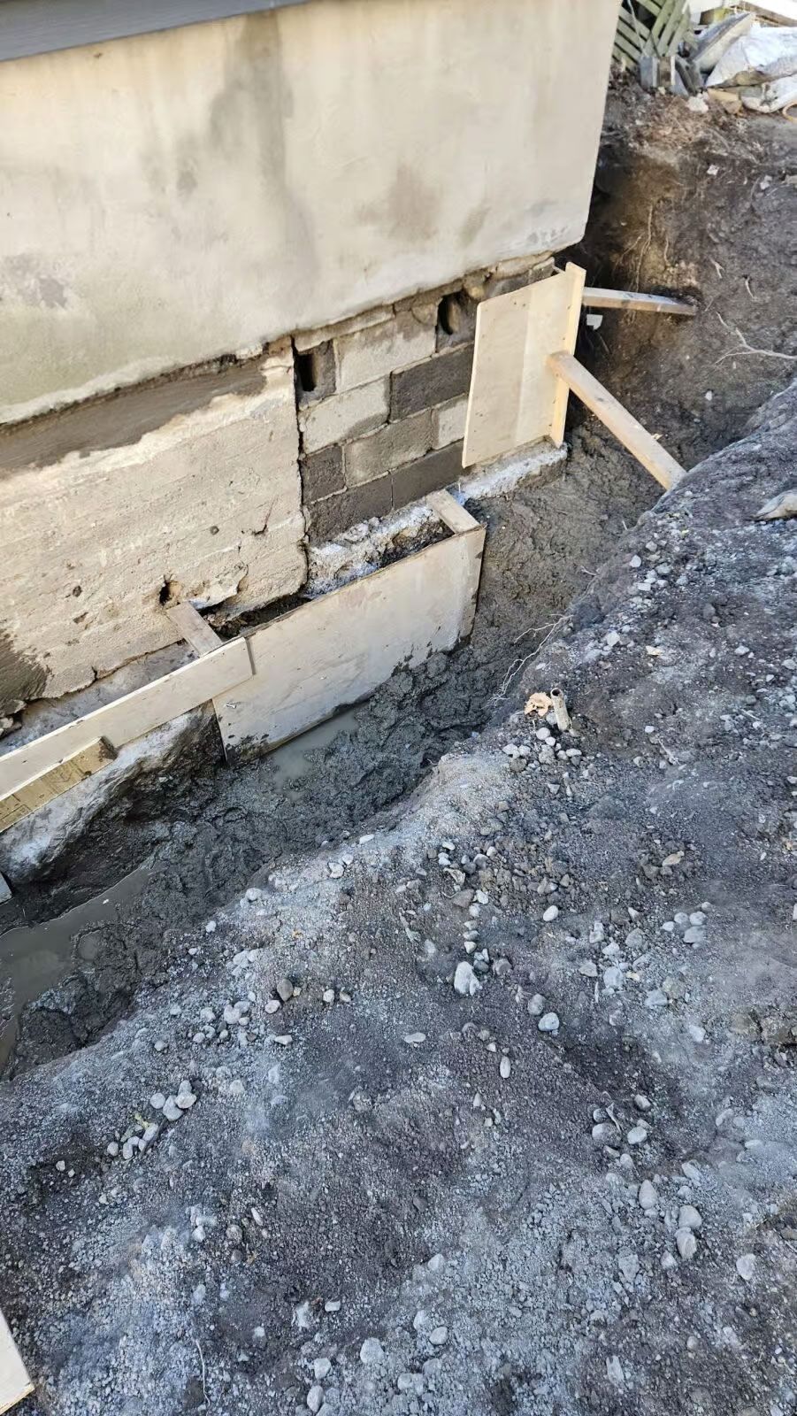 Réparation des fondations : Blocs et mortier exposés à la base d'une structure en béton lors d'une excavation.