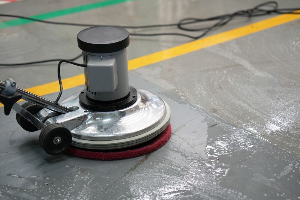 A machine is cleaning a concrete floor in a factory.