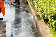 A person is using a high pressure washer to clean a sidewalk.