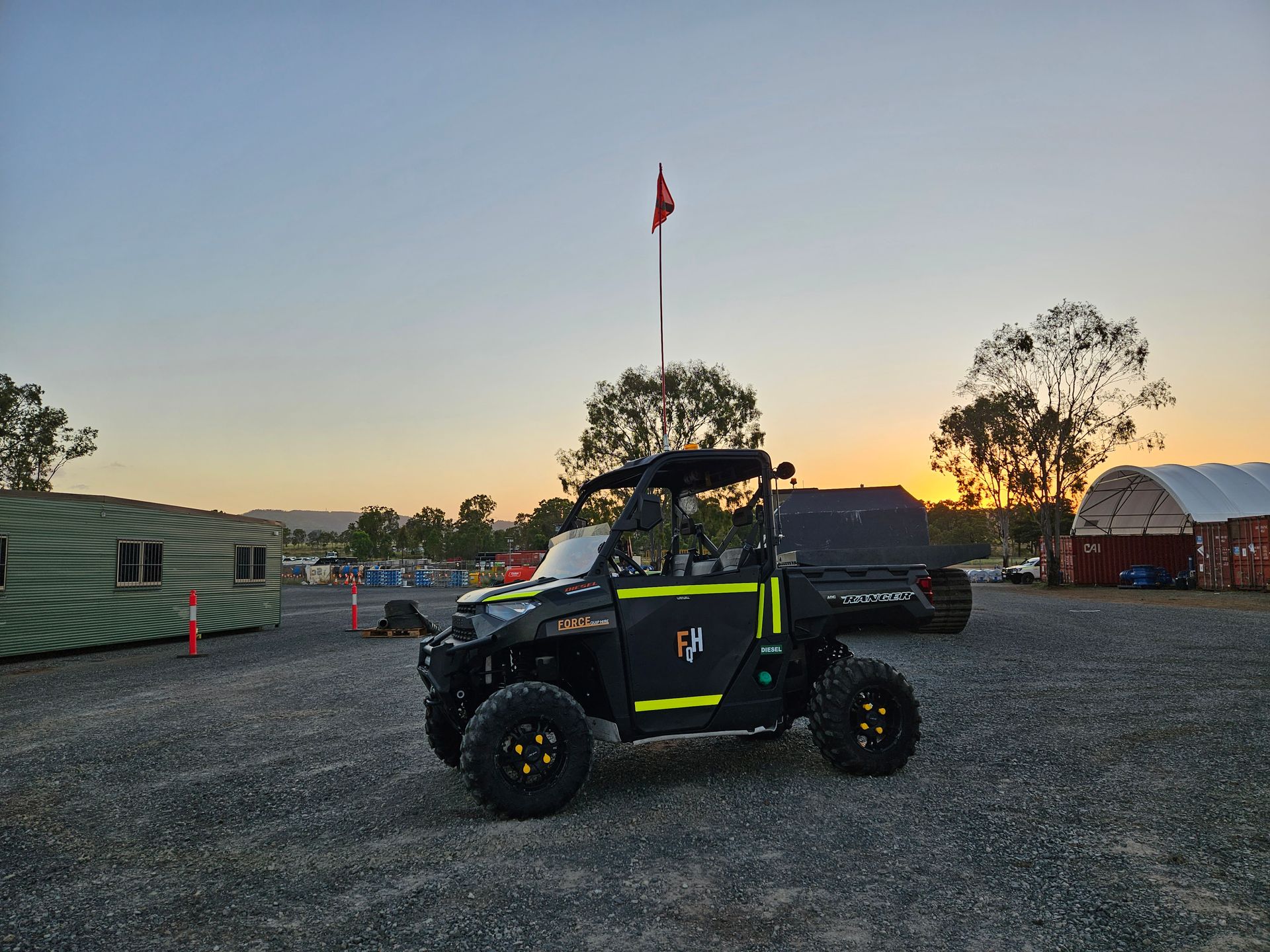 A Black And Yellow ATV Is Parked In A Gravel Lot At Sunset — Forcequip Hire In Southside, QLD