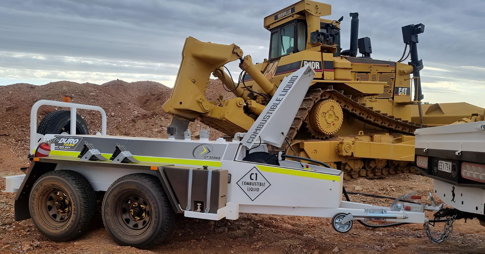 A Bulldozer Is Being Towed By A Trailer On A Dirt Road  — Forcequip Hire In Southside, QLD