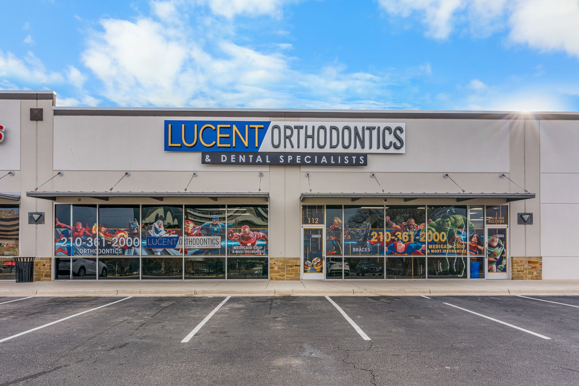 Exterior view of Lucent Orthodontics storefront in a strip mall, featuring large windows and parking spaces out front.
