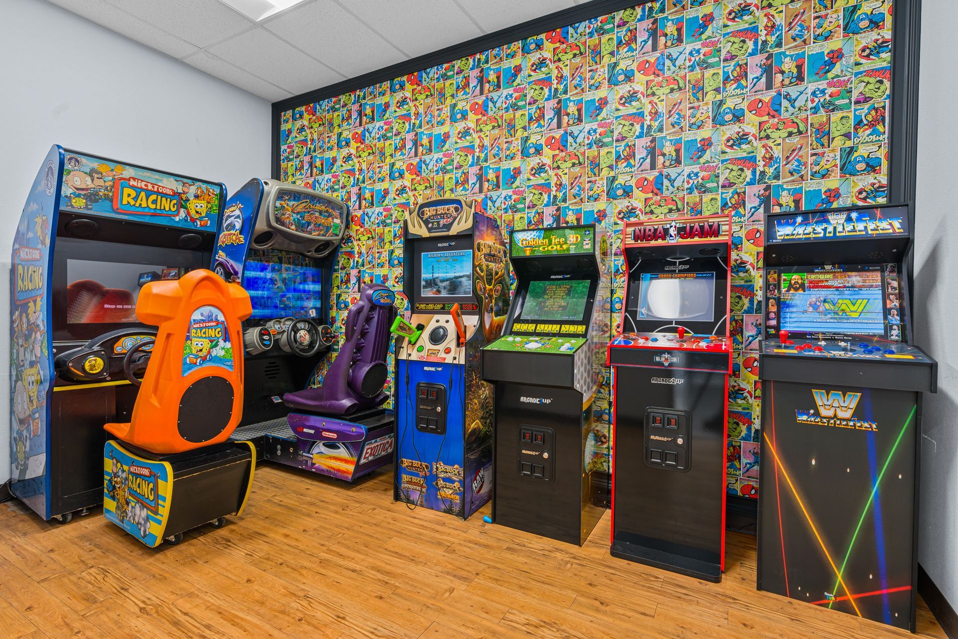 Lucent Orthodontics, San Antonio. A room with a comic book wallpaper features several arcade game cabinets and two racing simulators on a wooden floor.
