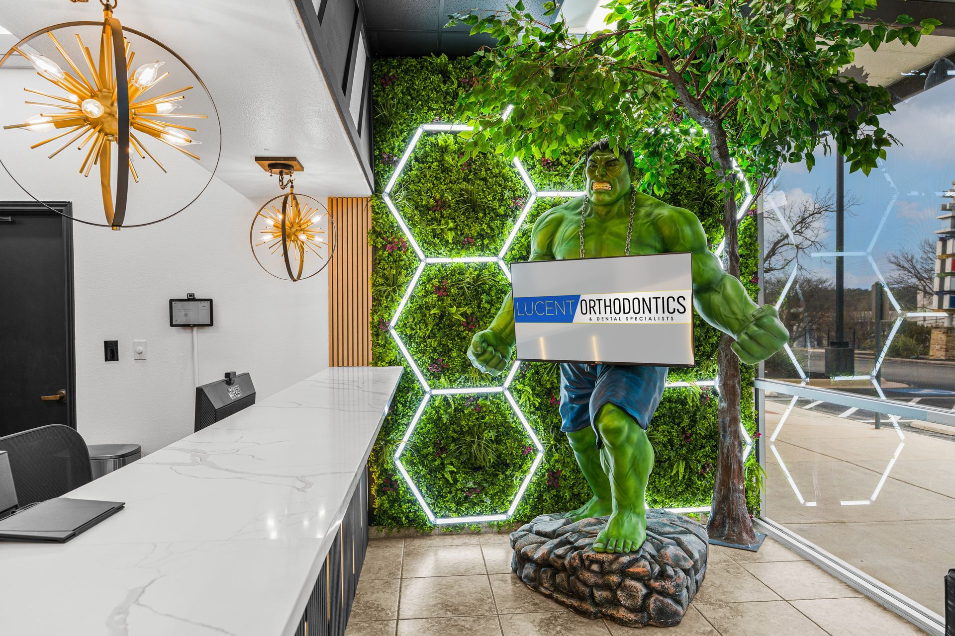 A Hulk statue stands in a modern office lobby in front of a green wall with glowing hexagon light frames.