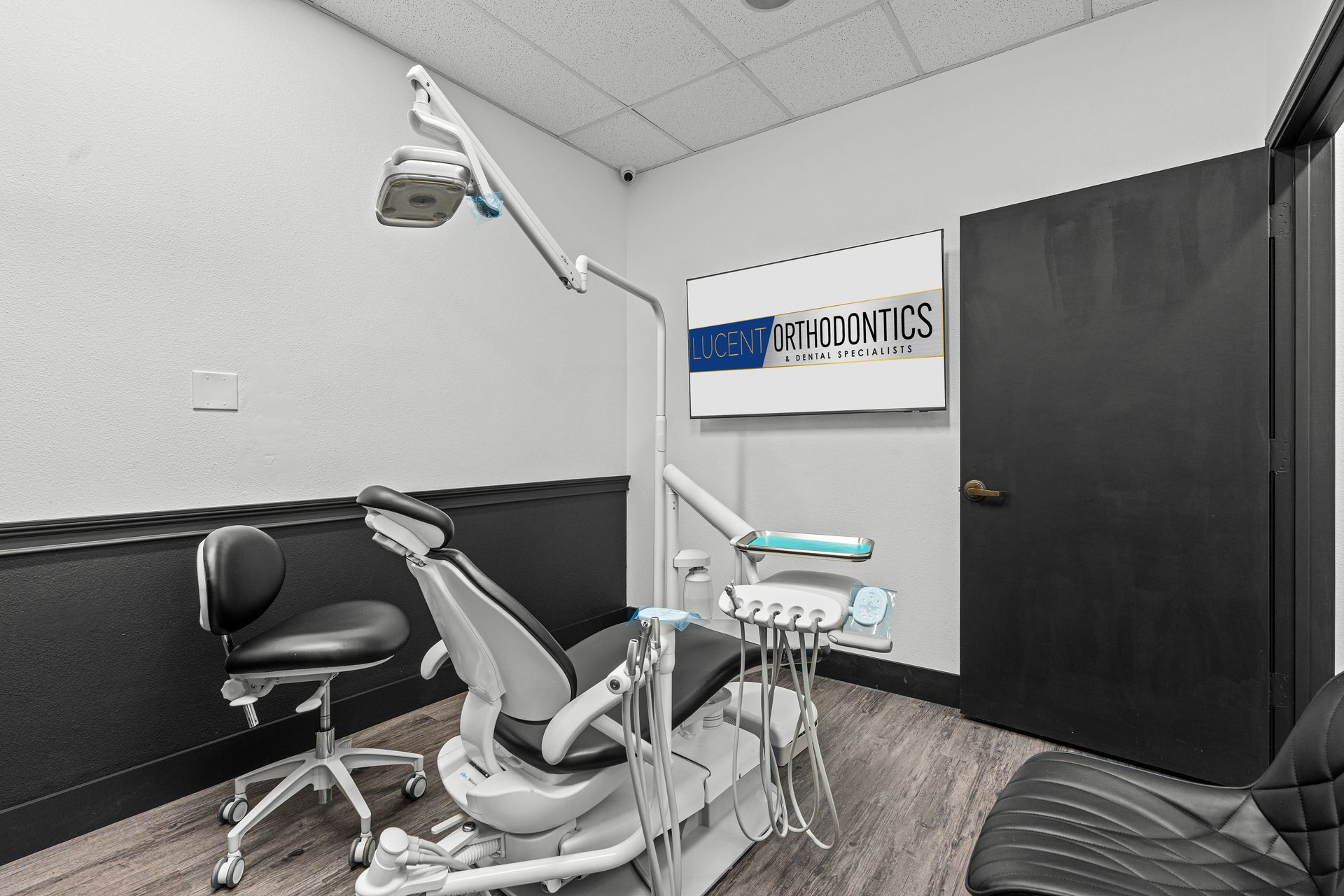 Lucent Orthodontics, San Antonio. A modern, bright orthodontist's office featuring a dental chair, examination light, and wall-mounted screen.