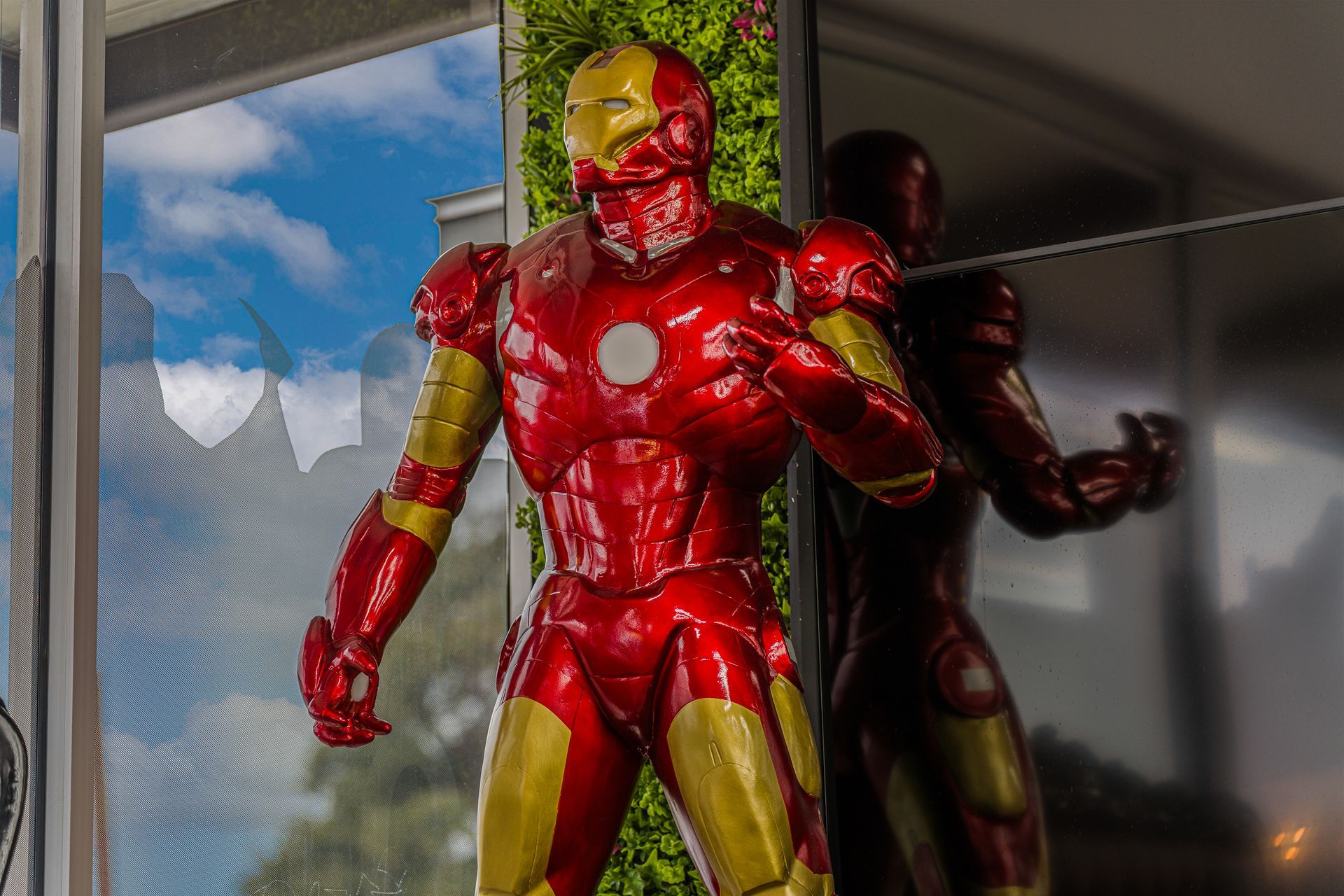 Lucent Orthodontics, San Antonio. A shiny red and gold Iron Man statue stands in front of a green wall and a glass window reflecting the sky.