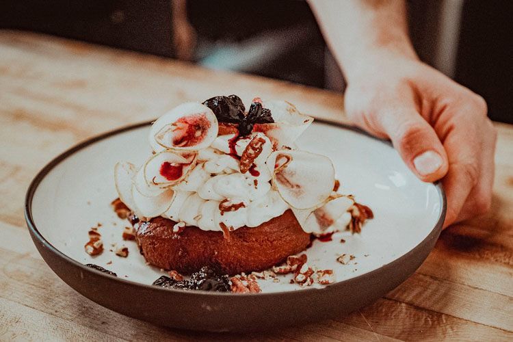 Une personne tient une assiette de nourriture sur une table en bois.