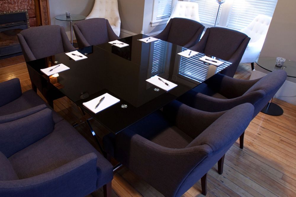 A conference room with a black table and purple chairs
