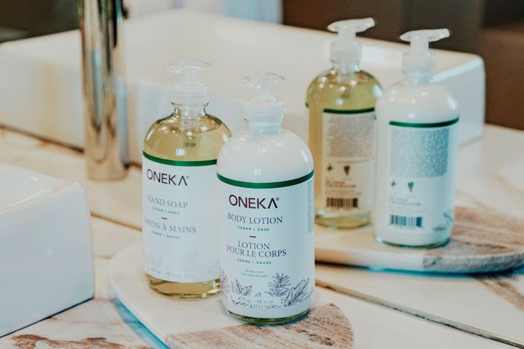 Three bottles of lotion are sitting on a counter next to a sink.