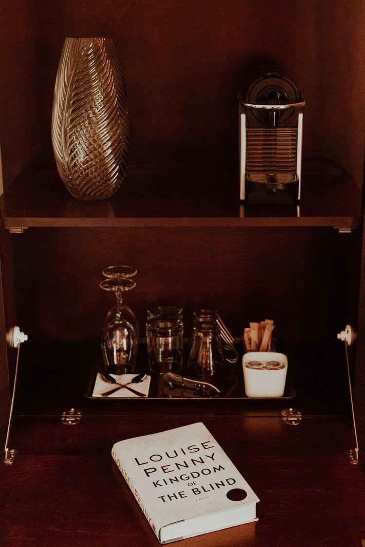 A book titled louisa sits on a shelf next to a vase and glasses.