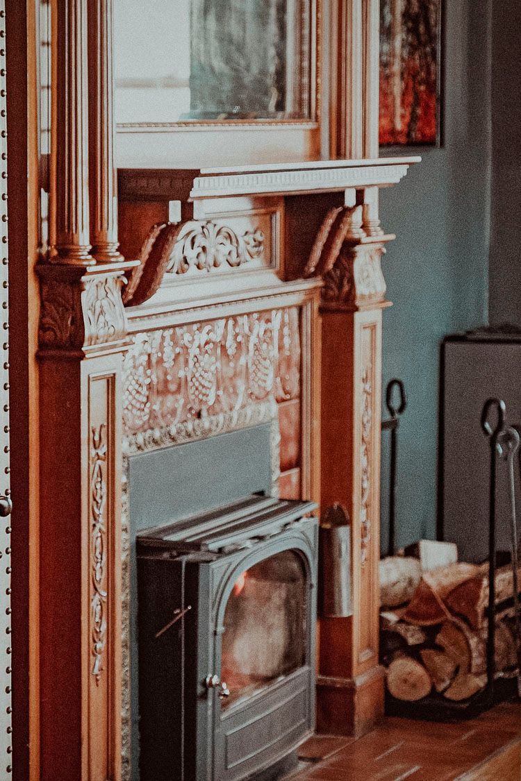 A fireplace with a wood stove and a mirror in a living room.