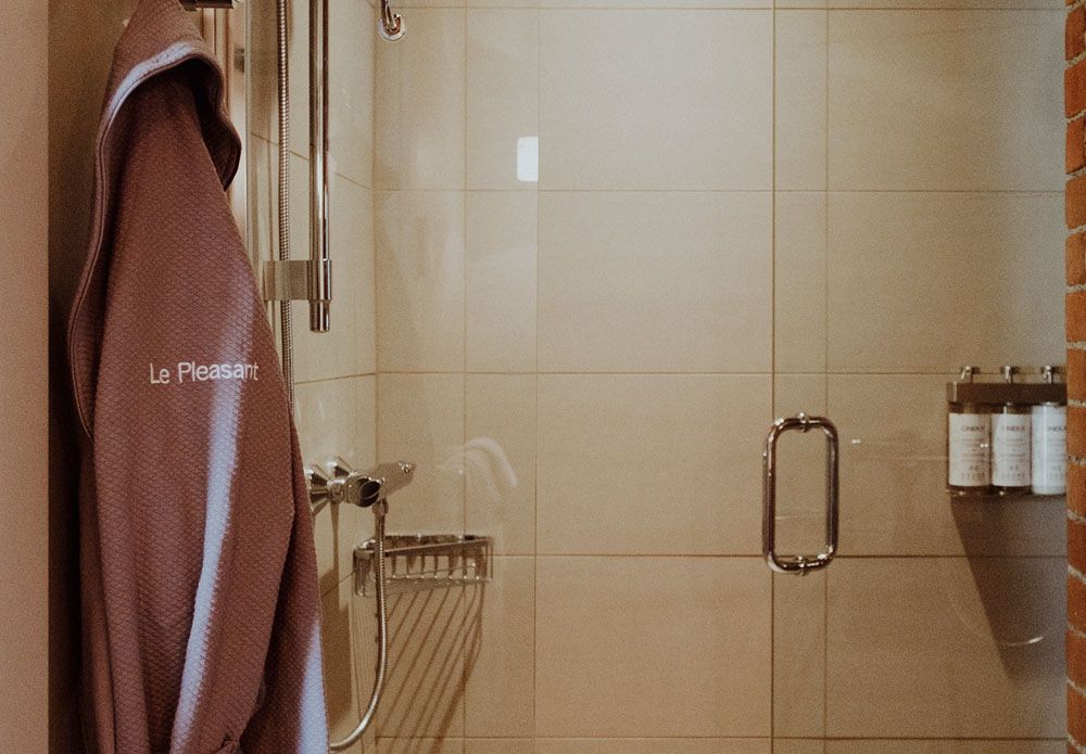 A robe is hanging in a bathroom next to a shower.