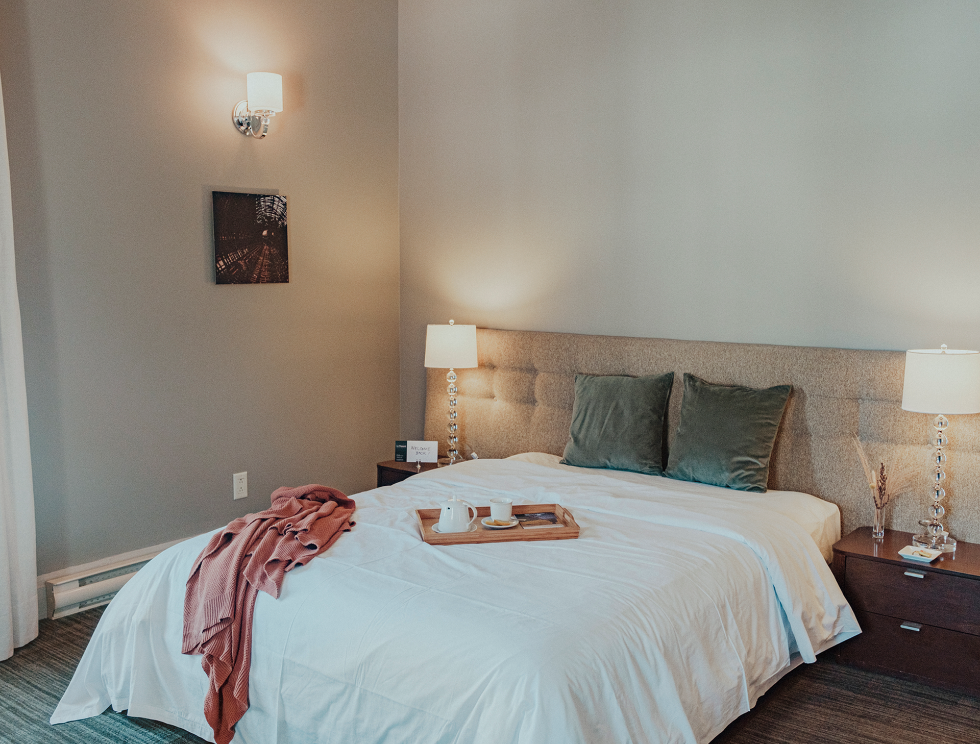 Une chambre d'hôtel avec un lit et un plateau avec de la nourriture et un café.