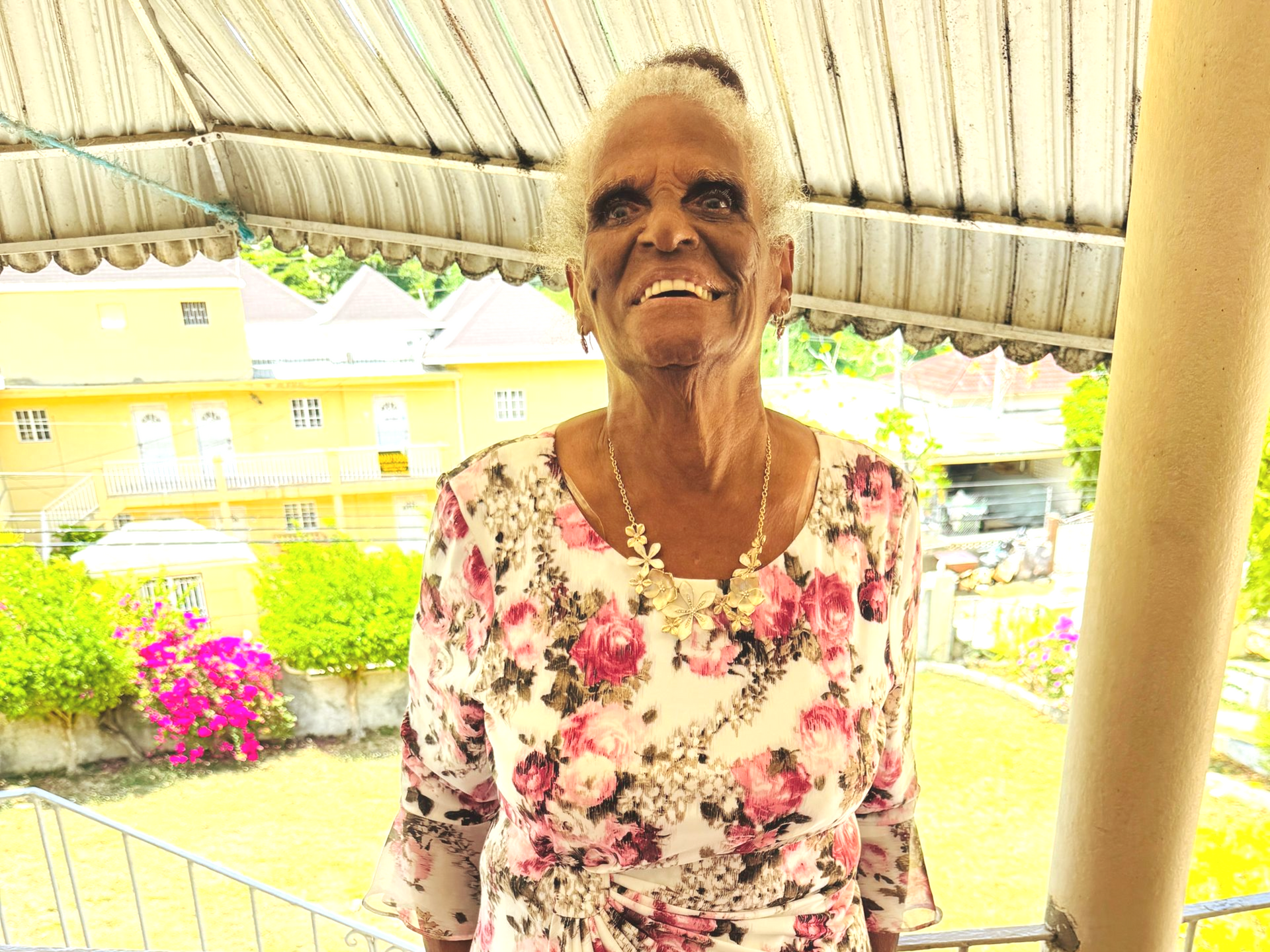 Miss May, co-namesake of the Vera May Foundation, smiling on her balcony in Jamaica