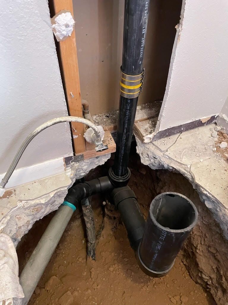 Plumbing pipes in a wall cavity; black and grey pipes connect.