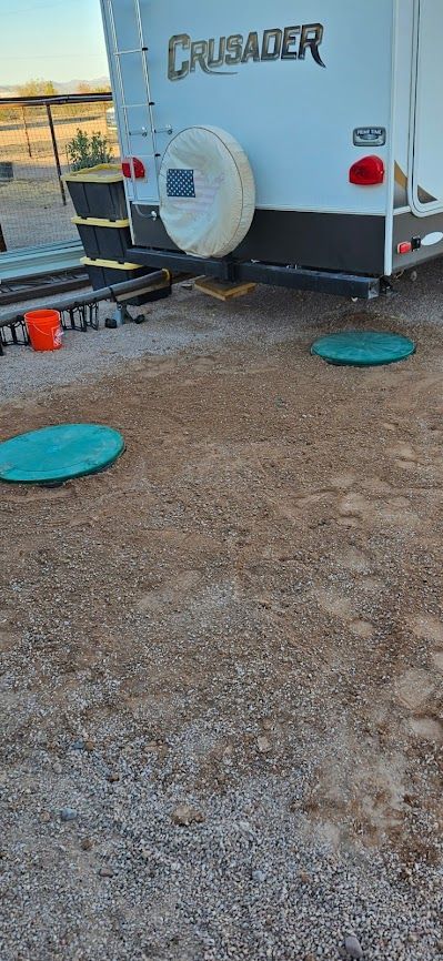Back of a Crusader RV with two green circular covers in gravel ground.