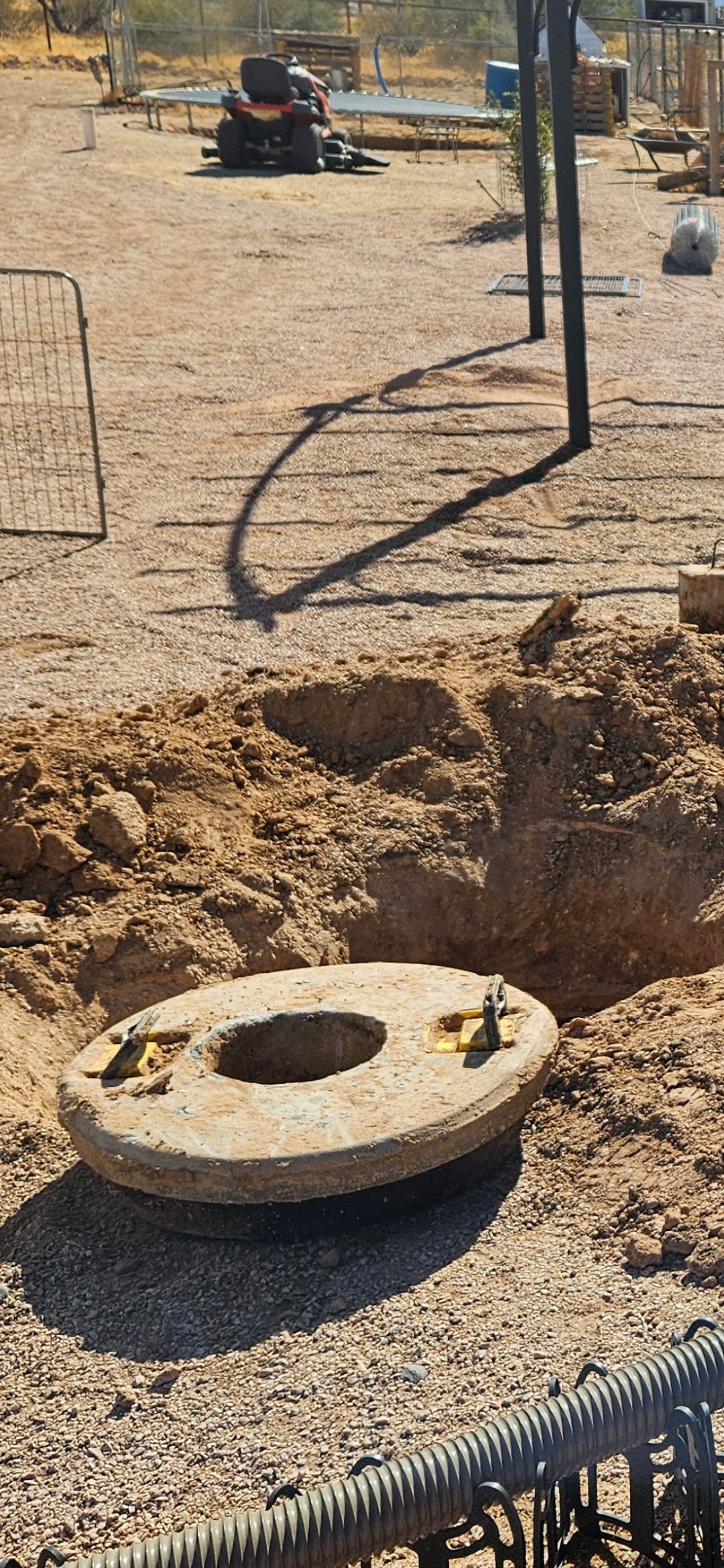 A concrete ring with a central hole, next to a pile of dirt and steel rebar. Construction site.