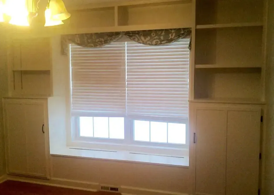 There is a window in the middle of the room with blinds on it.