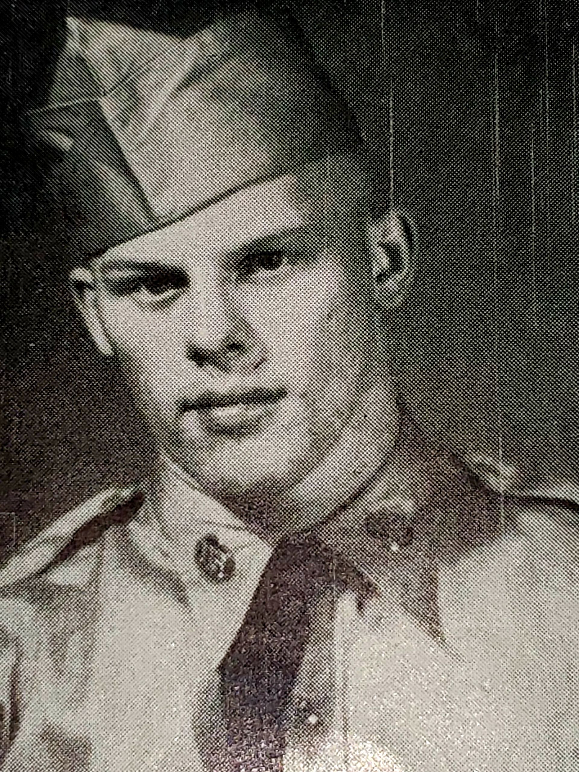 Man in military uniform, cap, and tie, looking at the camera. Black and white photograph.
