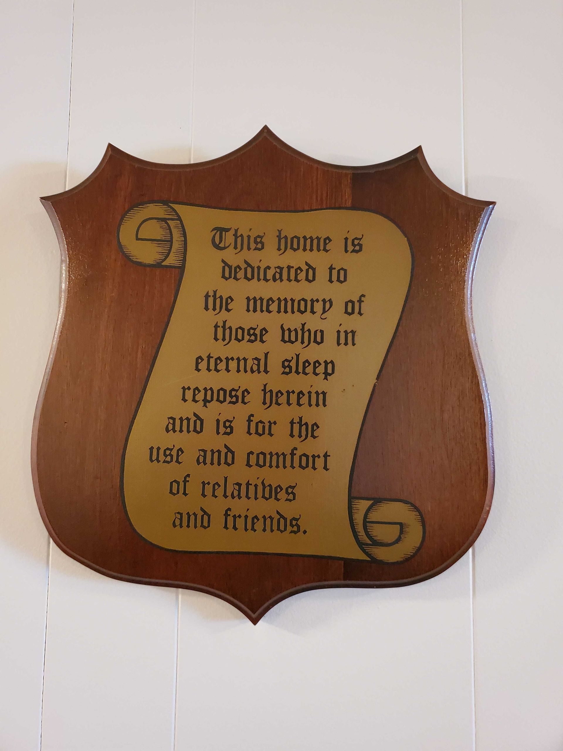 Wooden plaque with a scroll-shaped inscription honoring those resting in eternal sleep, for use and comfort of relatives and friends.