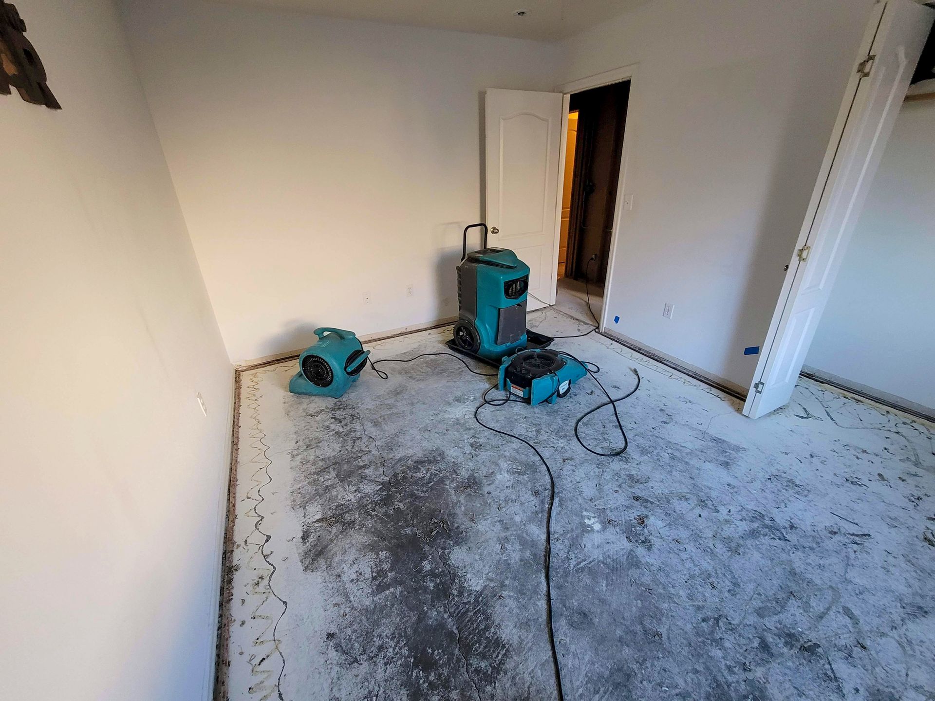 A water-damaged bedroom with carpet removed and air movers with a dehumidifier for drying