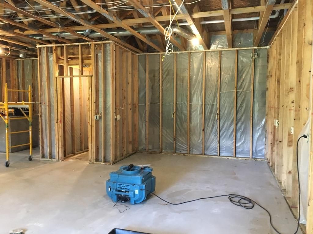 Basement under construction with wooden framing and a dehumidifier on the concrete floor.