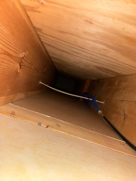 Looking up at a wooden duct between ceiling and wooden structure.