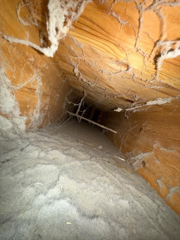 Close-up of a dusty HVAC duct opening surrounded by white, powdery debris.