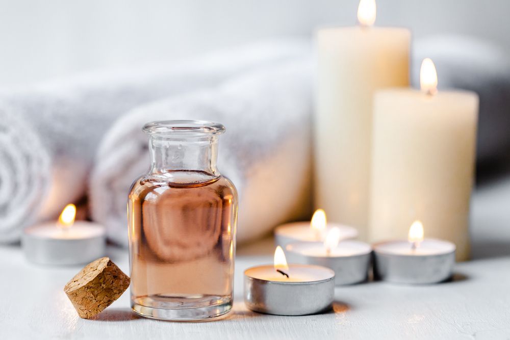 A Bottle of Essential Oil is Sitting on a Table Next to Candles and Towels — Your Body Revolution in Caloundra, QLD