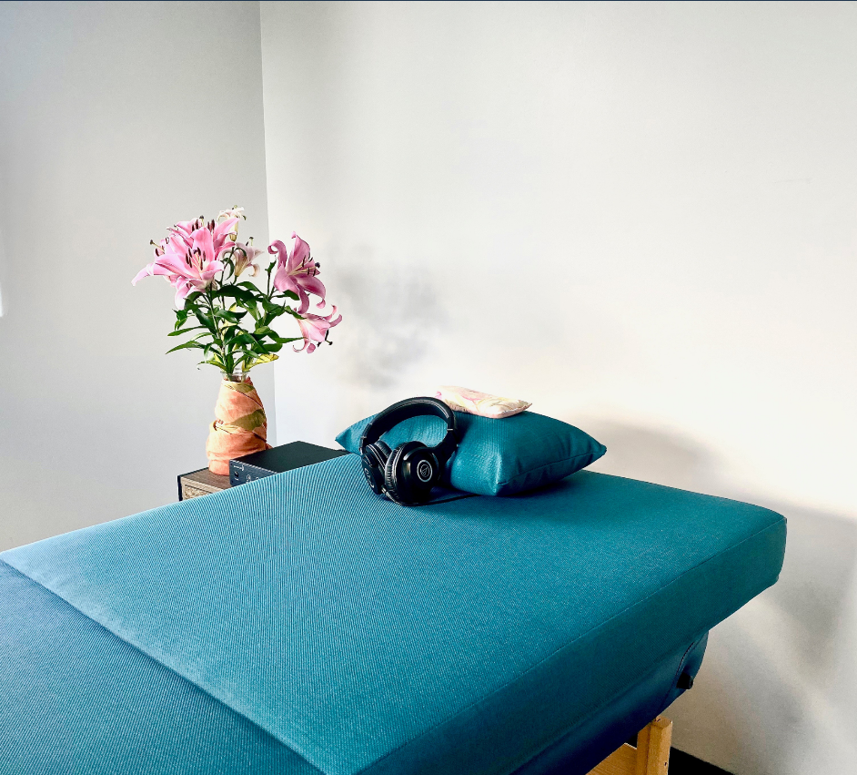 A Massage Table With a Vase of Flowers and Headphones on It — Your Body Revolution in Caloundra, QLD