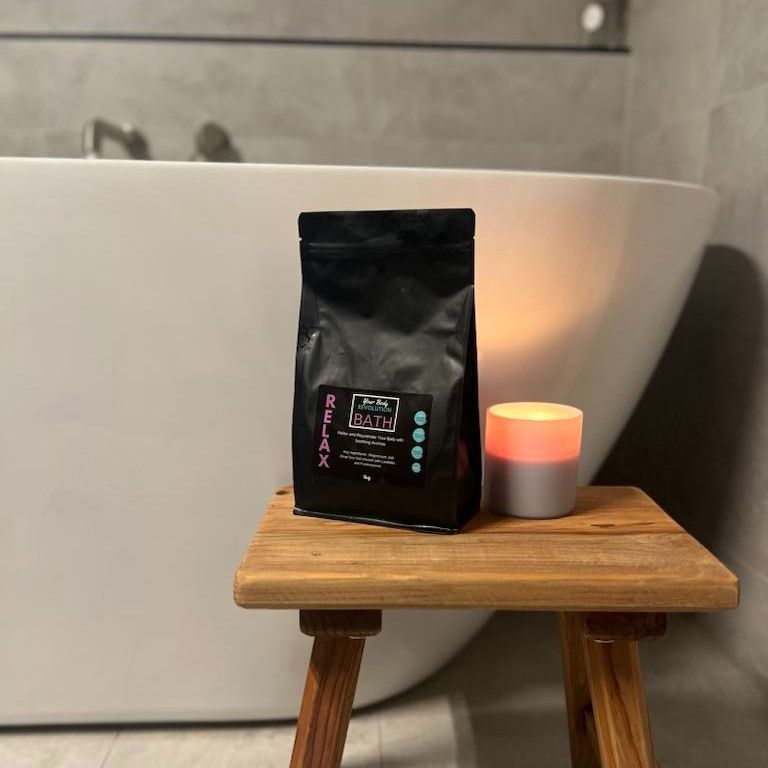 A Bag of Bath Salt is Sitting on a Wooden Stool in Front of a Bathtub — Your Body Revolution in Caloundra, QLD