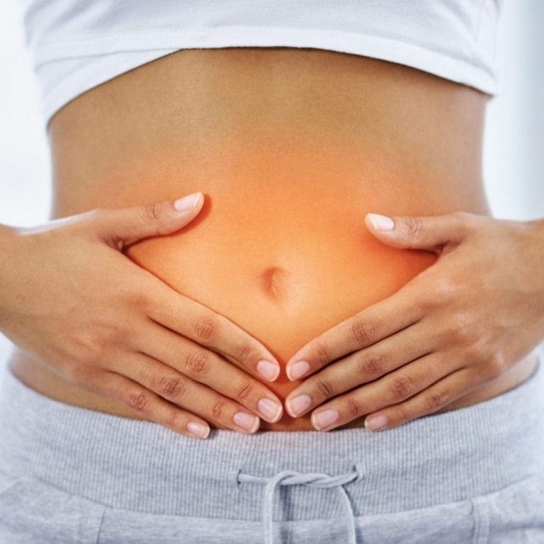 A Woman is Holding Her Stomach in Pain — Your Body Revolution in Caloundra, QLD
