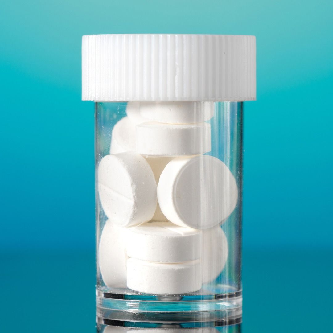 A Glass Bottle Filled With White Pills on a Blue Background — Your Body Revolution in Caloundra, QLD