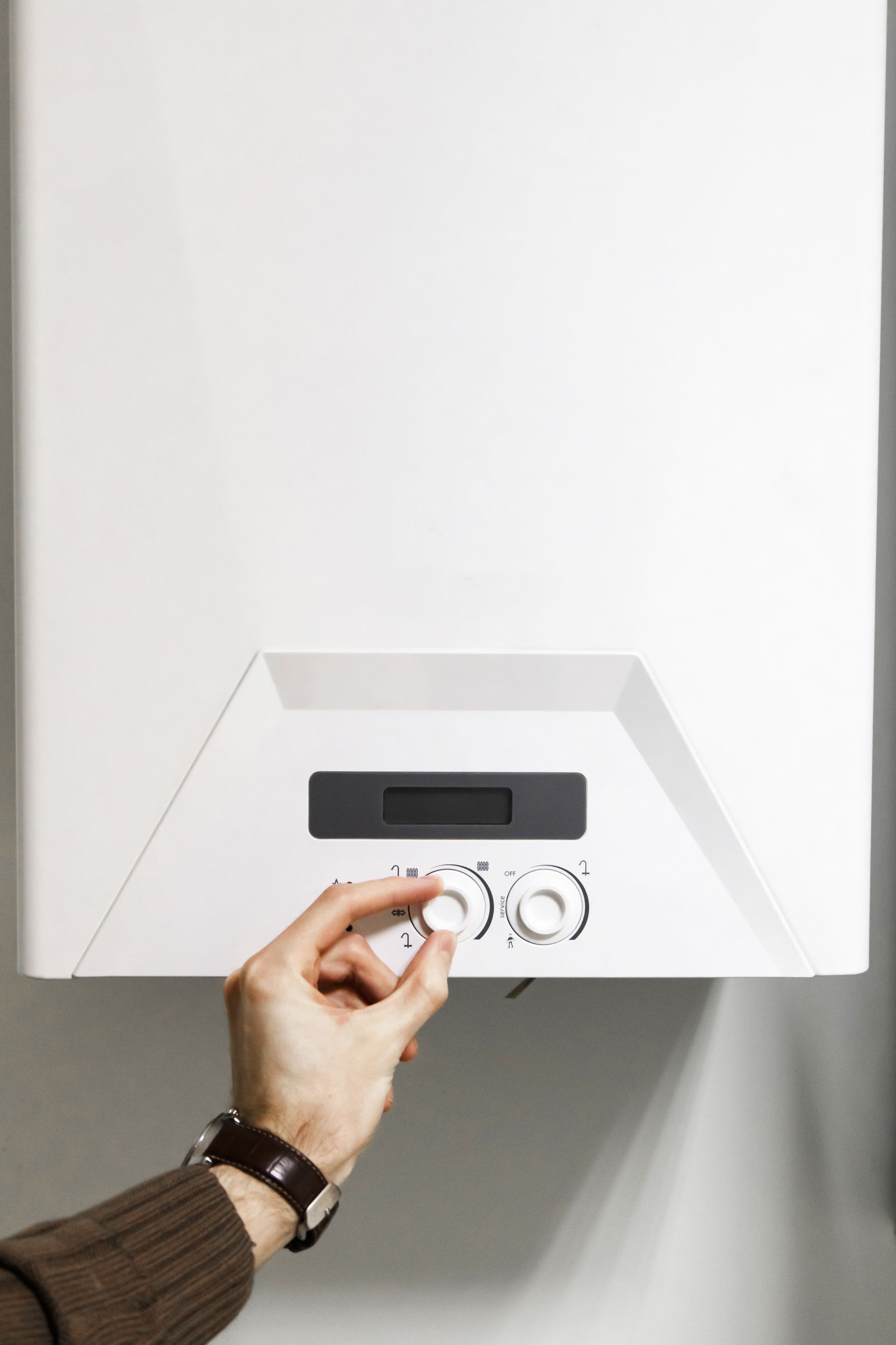 A person is pressing a button on a boiler.