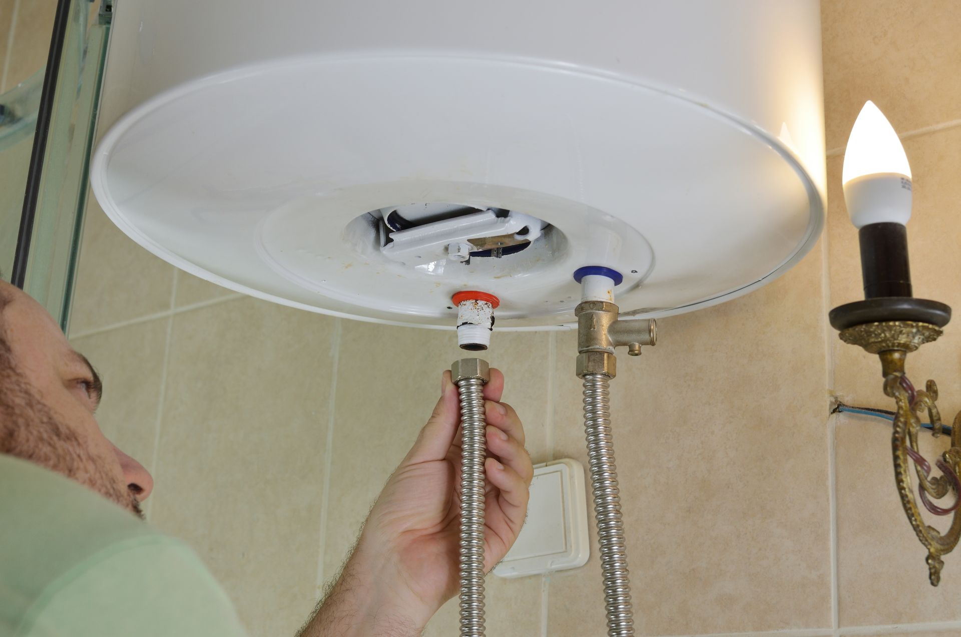 A person is fixing a water heater in a bathroom