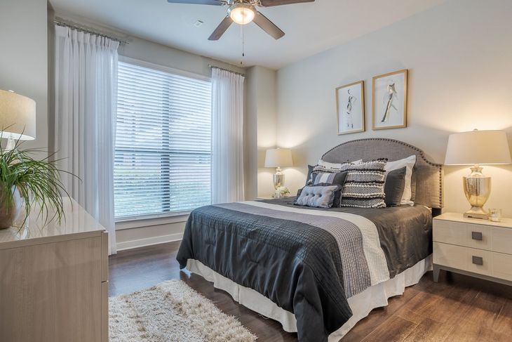 Bedroom with a bed, nightstands, dresser, window, and ceiling fan, featuring neutral tones and decorative accents.