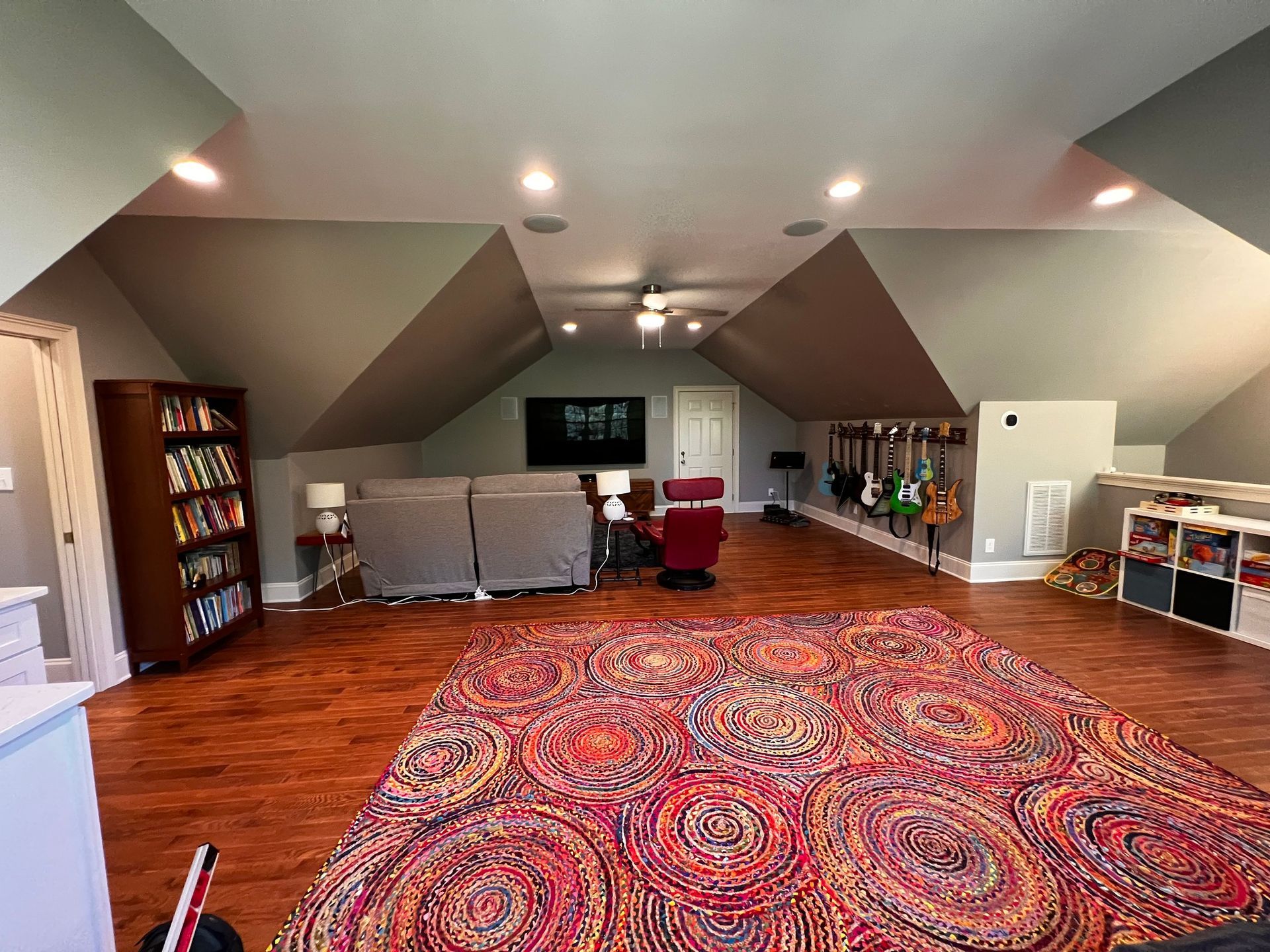 A living room with hardwood floors , a rug , a couch and a television.
