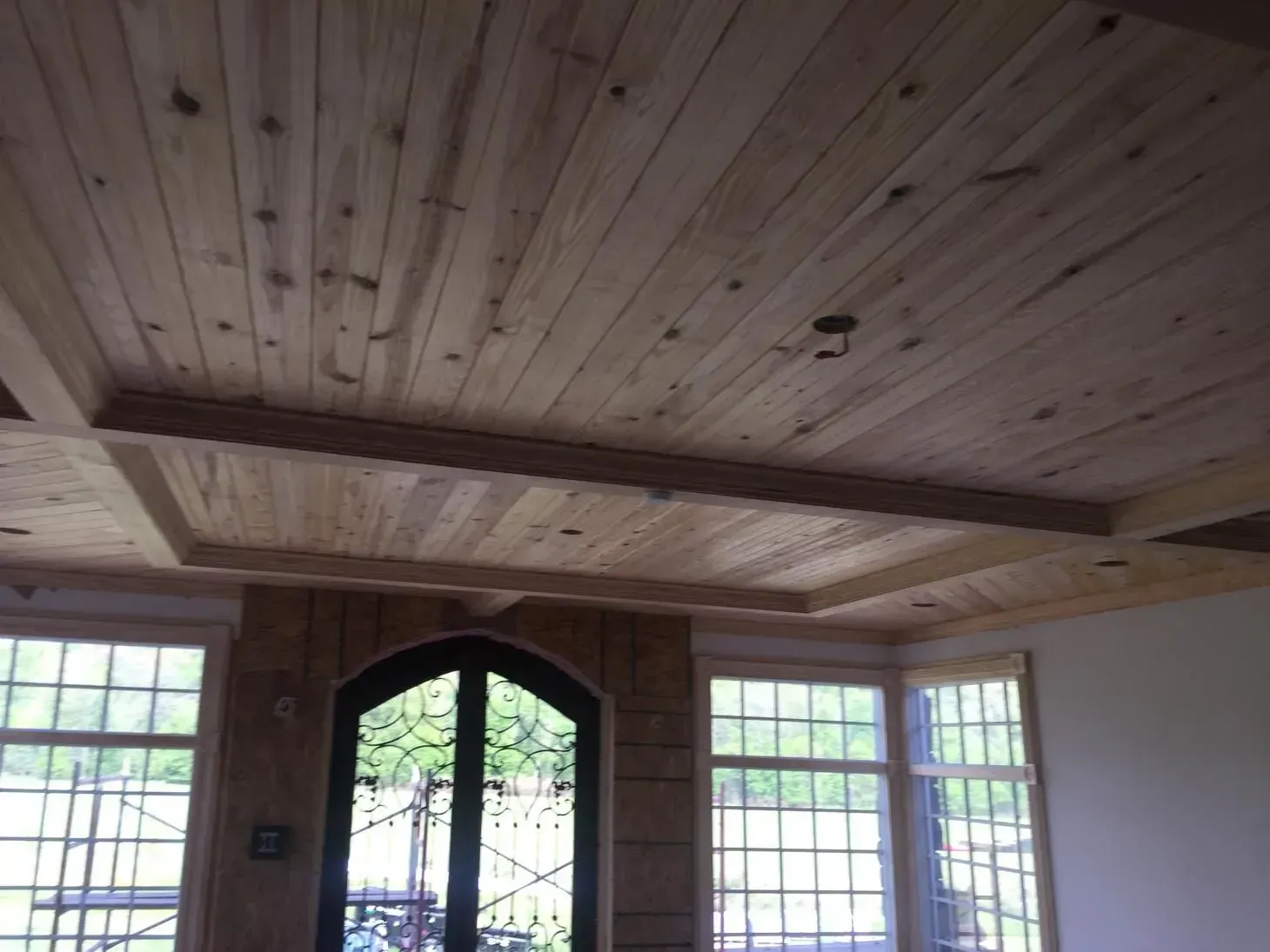 Wooden ceiling with a coffered design, above windows and a door. Natural wood tone.