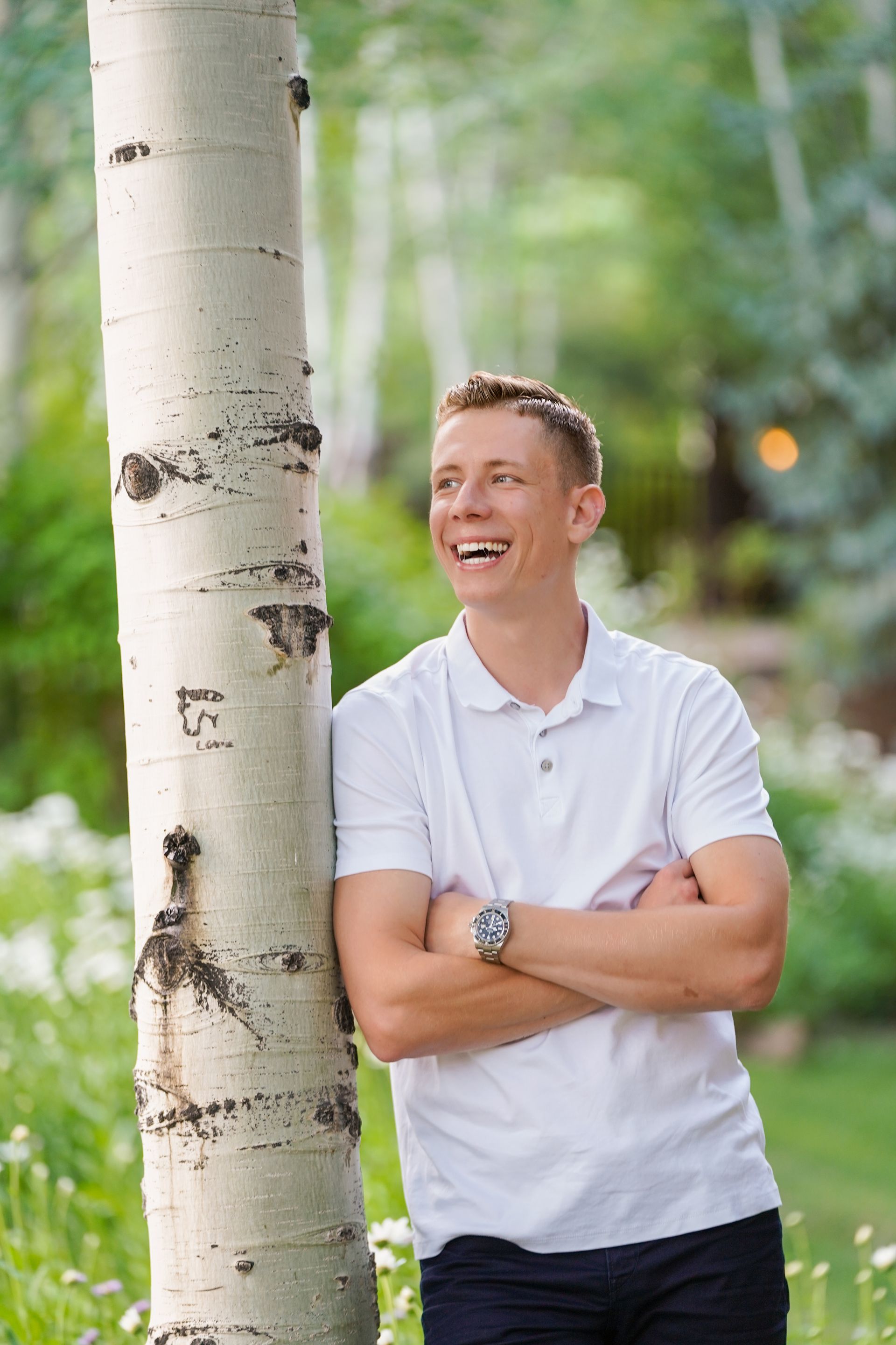 A woman is sitting at a desk with a laptop and a vase of flowers.