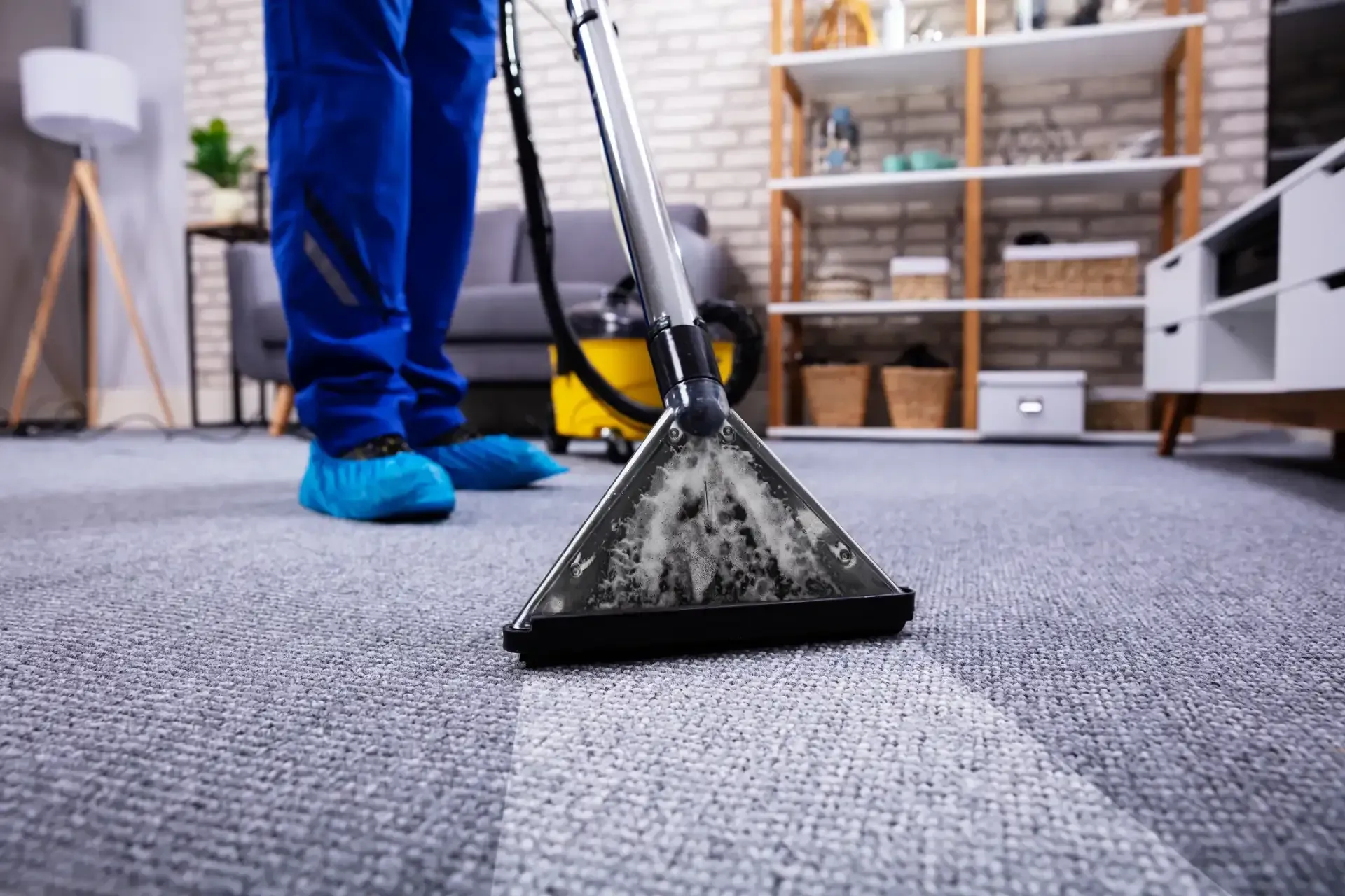 A person is cleaning a carpet with a vacuum cleaner in a living room.